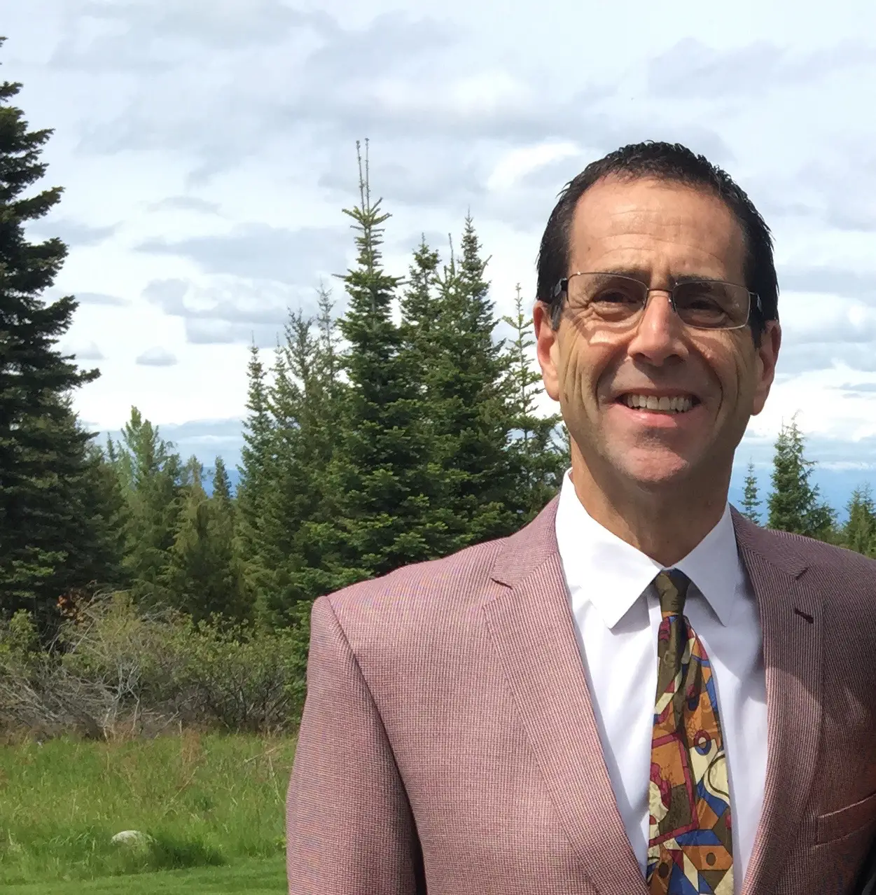 A man in a pink suit standing next to some trees.